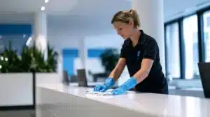 מנקה בערב מנגבת דלפק קבלה ארוך בלובי משרד ריק עם מטלית מיקרופייבר